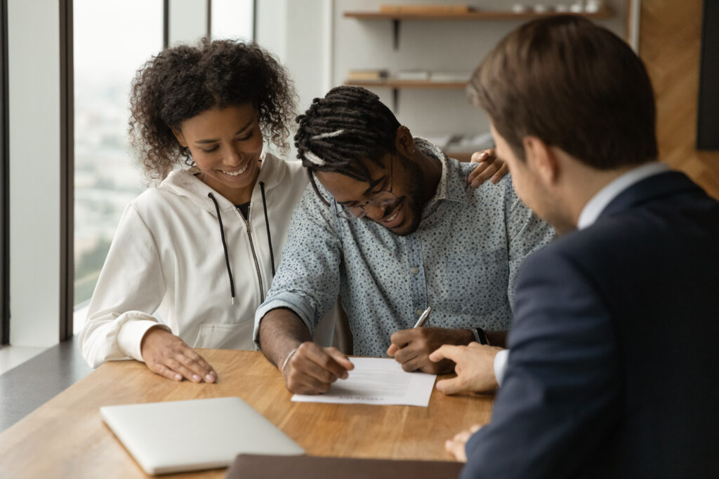 young couple signing papers with an agent so they can build credit with a loan