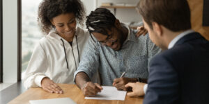 young couple signing papers with an agent so they can build credit with a loan