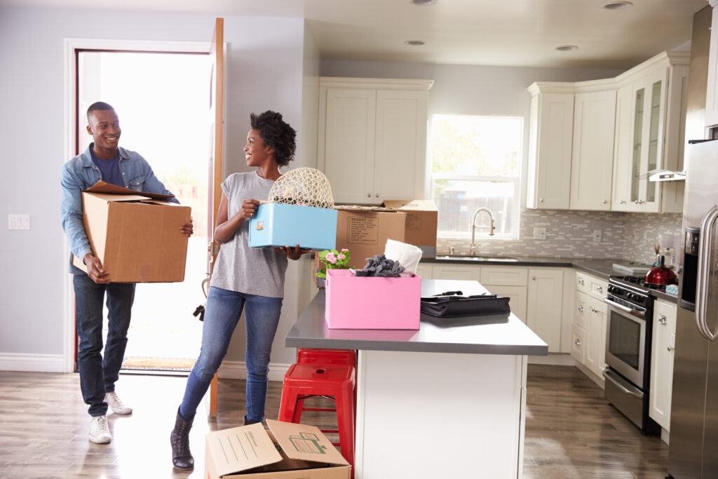 young couple carrying boxes into their new kitchen