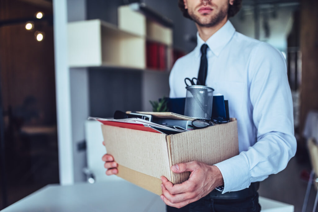 man holding box of belongings after an unexpected job loss