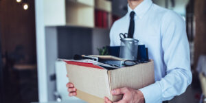 man holding box of belongings after an unexpected job loss