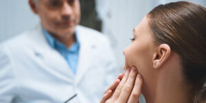 woman touching her mouth and asking her dentist about the best borrowing options for unexpected dental expenses