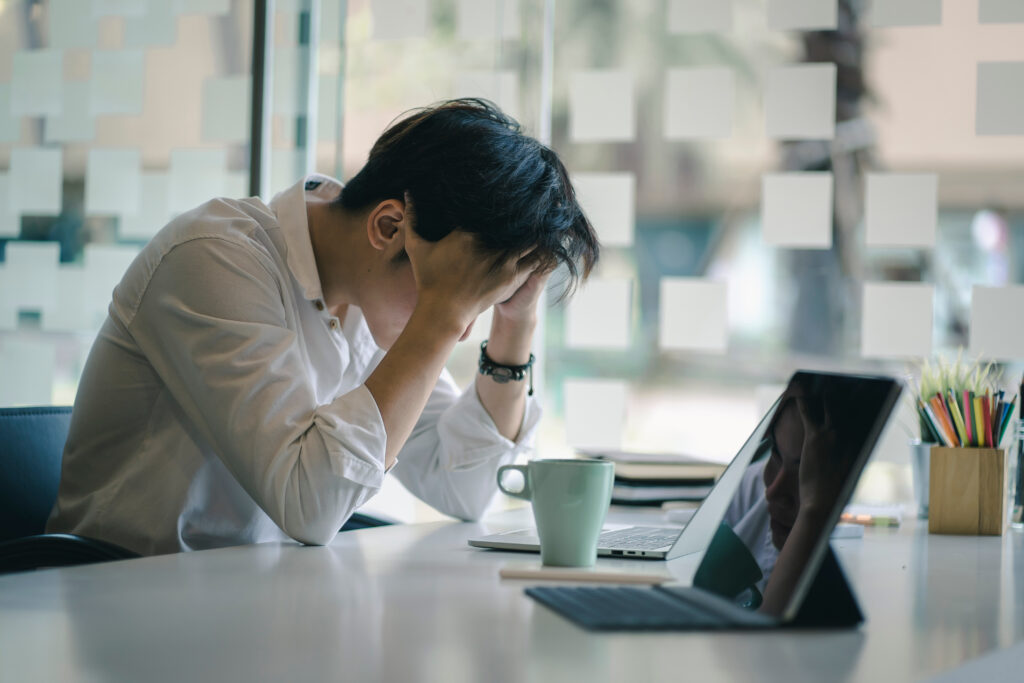 man with his head in his hands because of the financial stress on his mental health