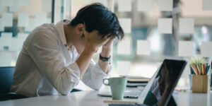 man with his head in his hands because of the financial stress on his mental health