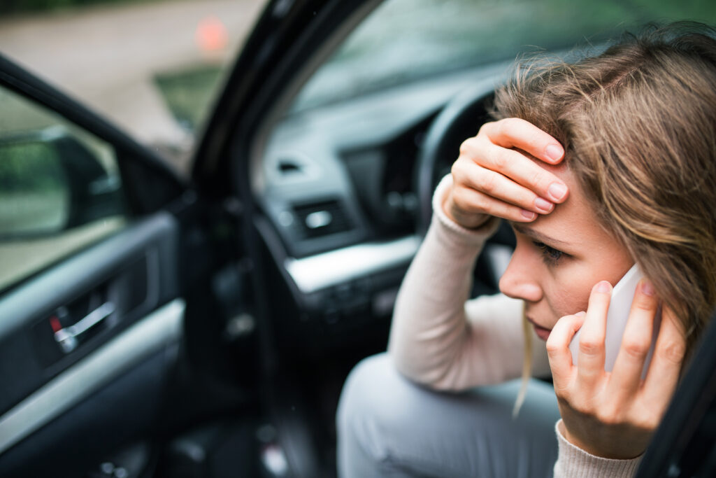 young woman on the phone in her car because she can't afford car insurance