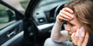 young woman on the phone in her car because she can't afford car insurance