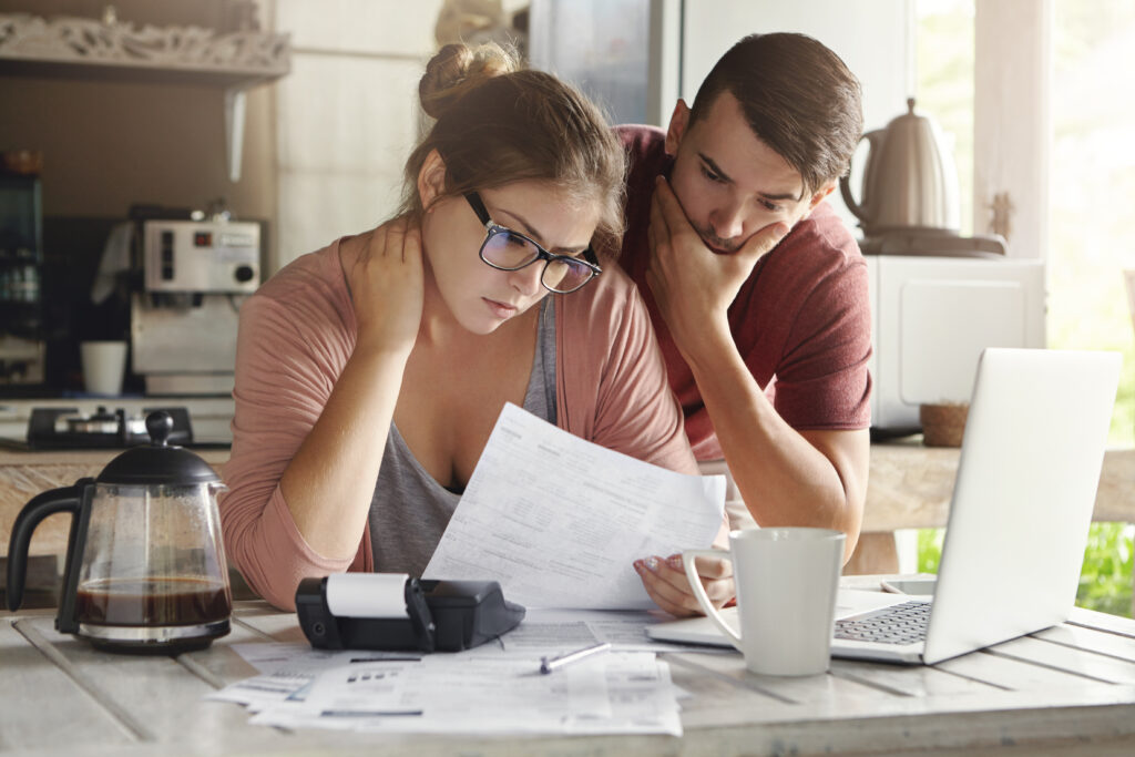 young couple learning 8 methods of paying down debt at their kitchen counter