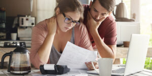 young couple learning 8 methods of paying down debt at their kitchen counter