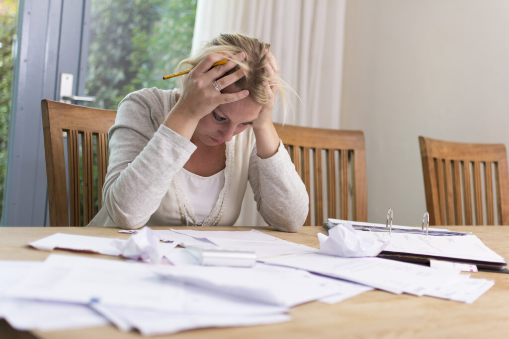 woman with hands on her head frustrated by bills