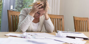 woman with hands on her head frustrated by bills