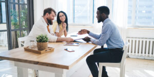 a young couple sitting at a table with an agent asking questions about renters insurance