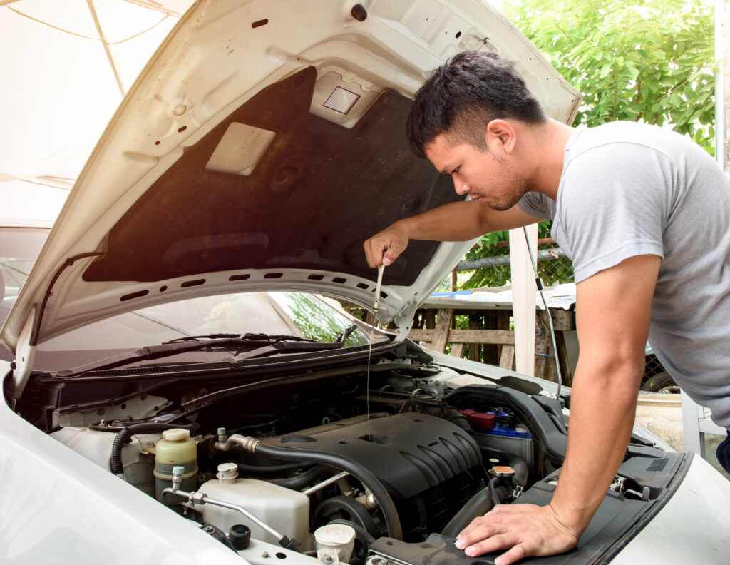 young man checking the oil to extend the lifespan of his car