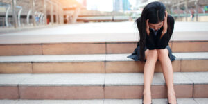 woman sitting on steps with her hands on her head wondering how to get insurance when you're unemployed